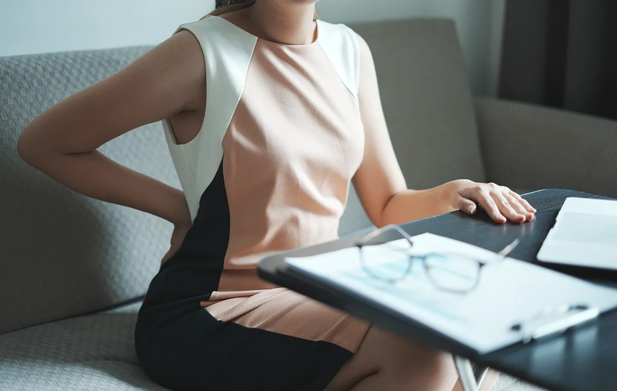 office woman sitting at a desk holding her back - back pain