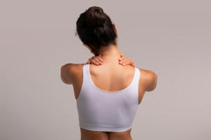 Self-adjustments, woman massaging her neck on grey background