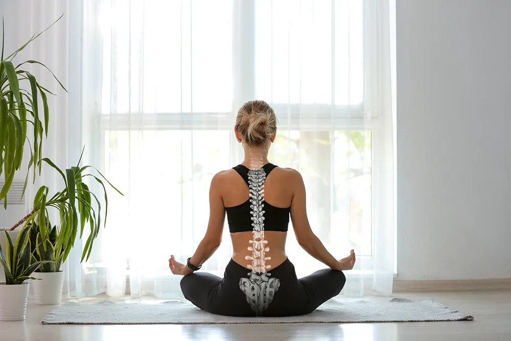 Blonde woman doing yoga facing a window this spine and back highlighted