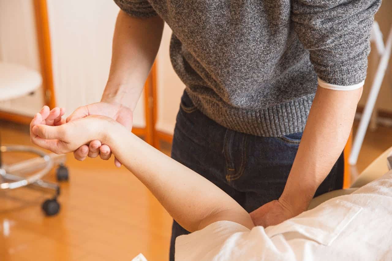 A close-up of a hand massage therapy session, focusing on the hands and arms.